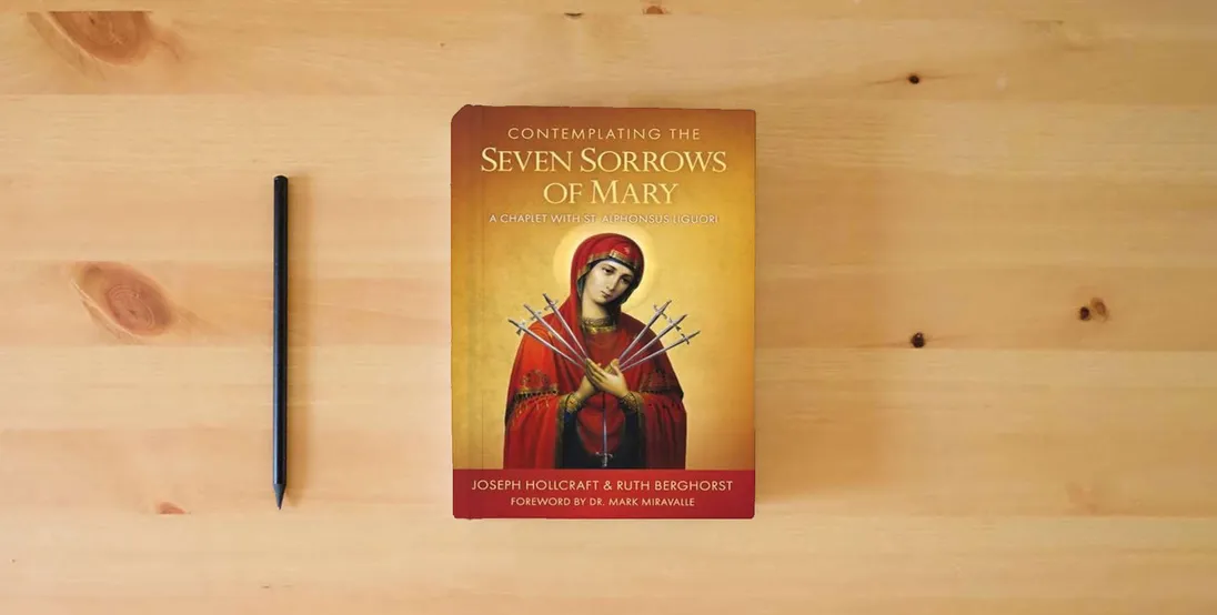 The book Contemplating the Seven Sorrows of Mary: A Chaplet with St. Alphonsus Liguori} is on the table