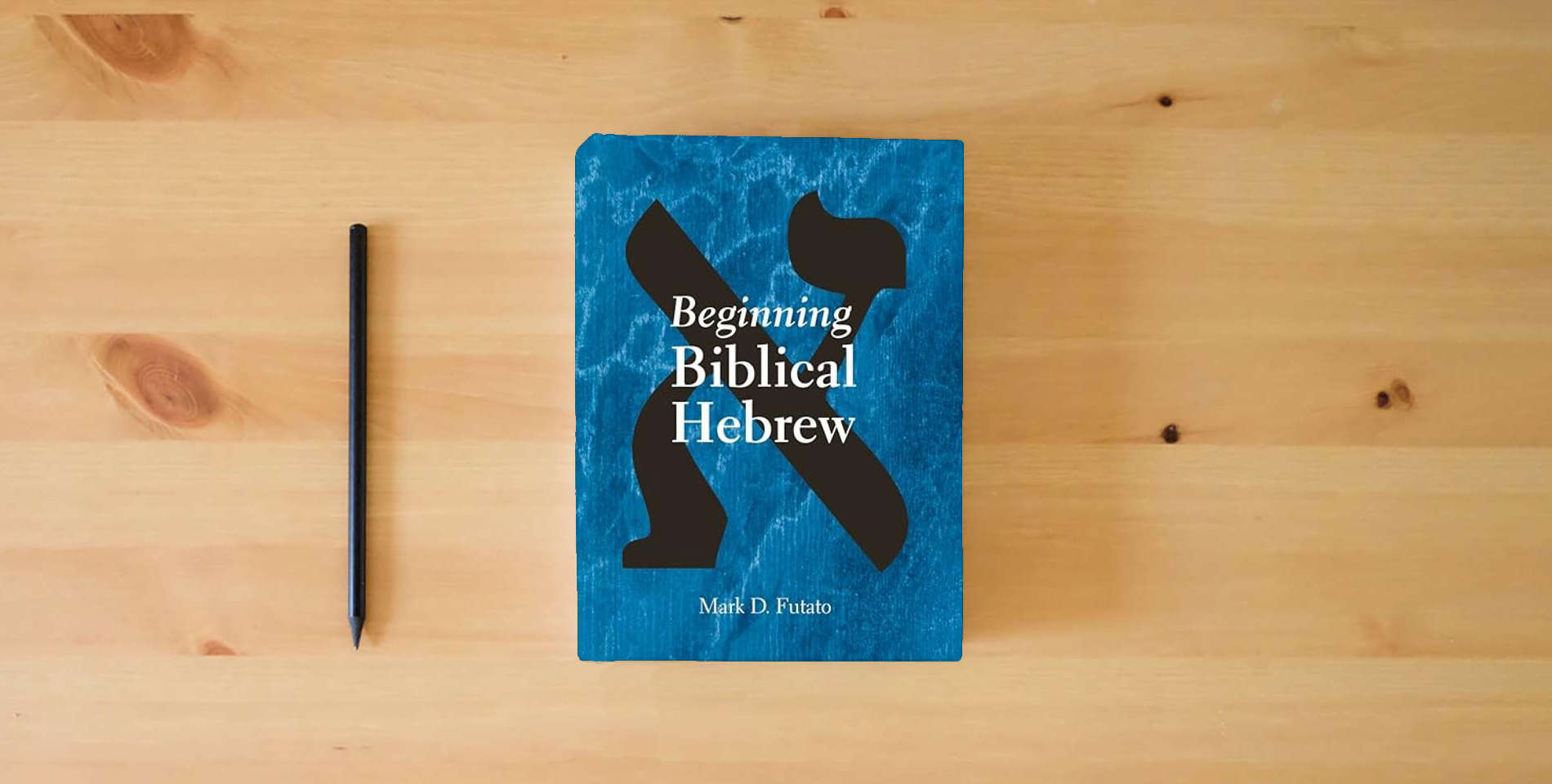 The book Beginning Biblical Hebrew is on the table
