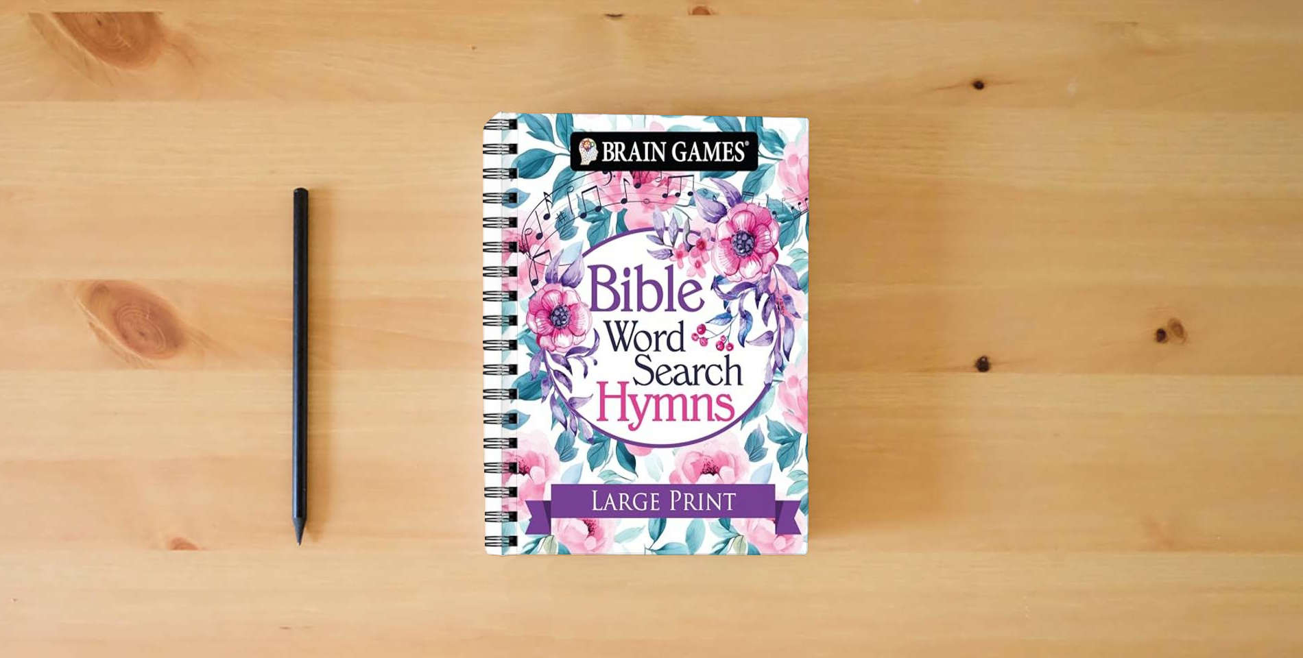 The book Brain Games - Bible Word Search: Hymns - Large Print is on the table