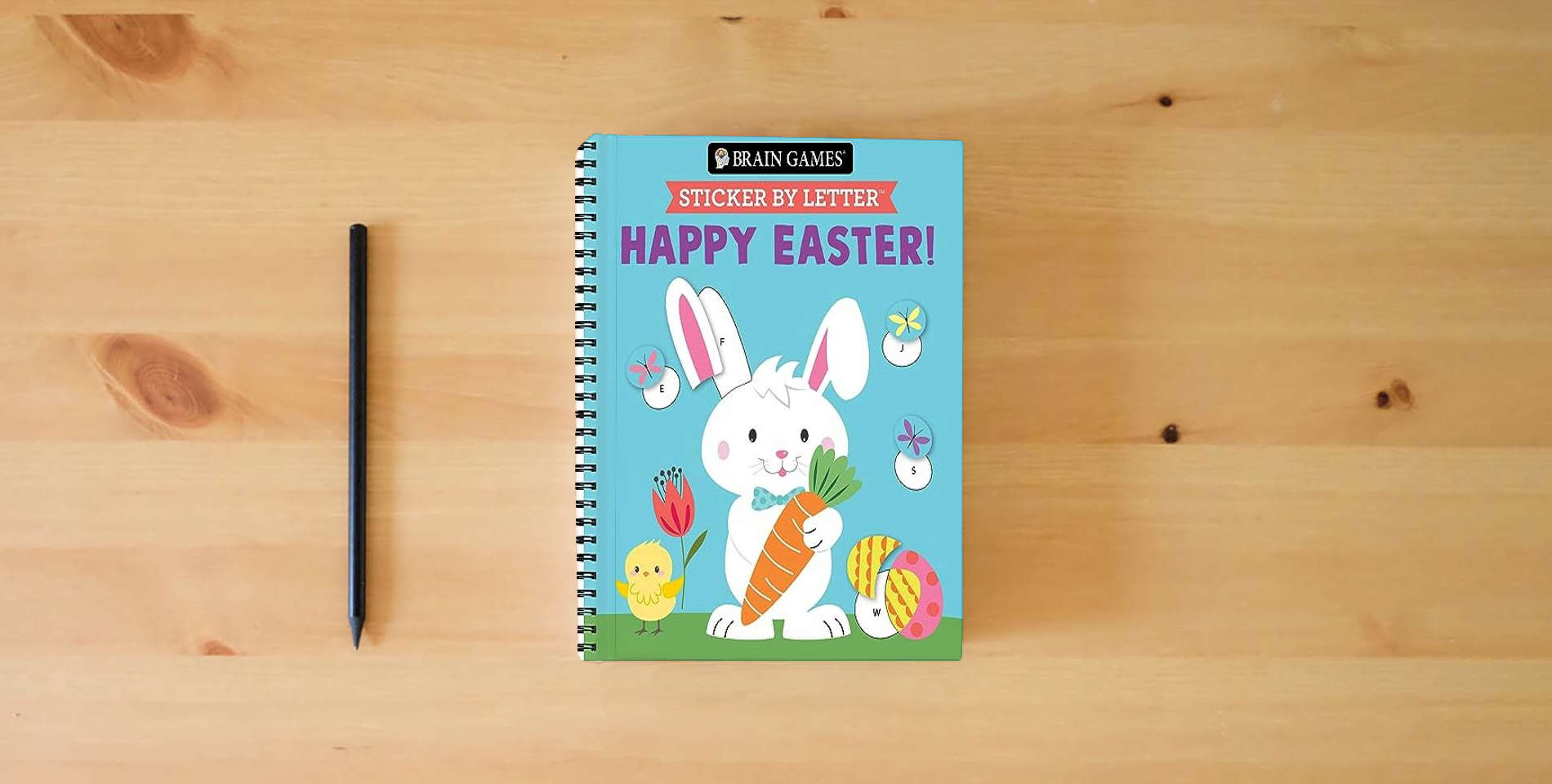 The book Brain Games - Sticker by Letter: Happy Easter! is on the table