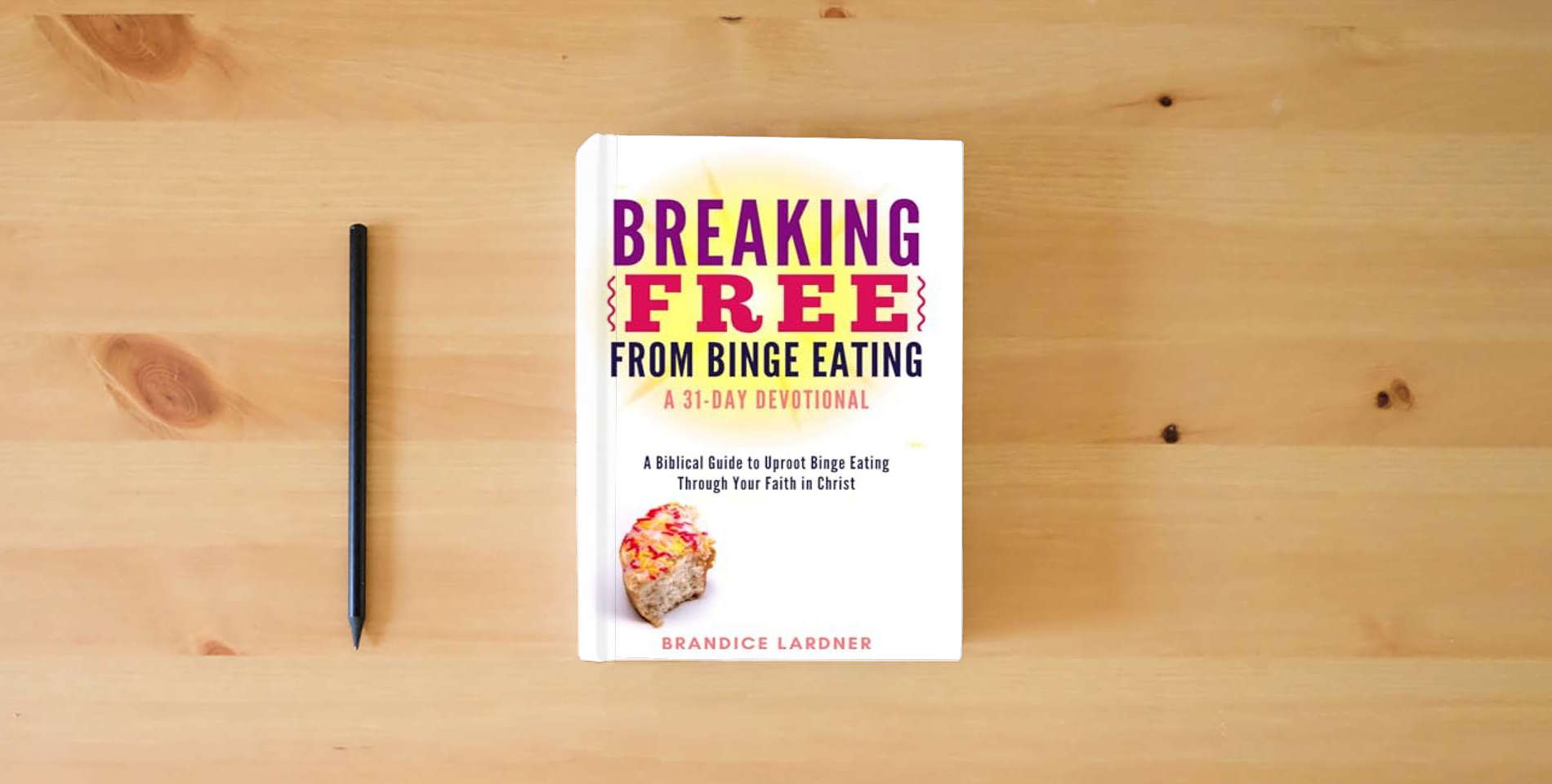 The book Breaking Free From Binge Eating: A Biblical Guide to Uproot Binge Eating Through Your Faith in Christ (A Transformative Devotional) is on the table