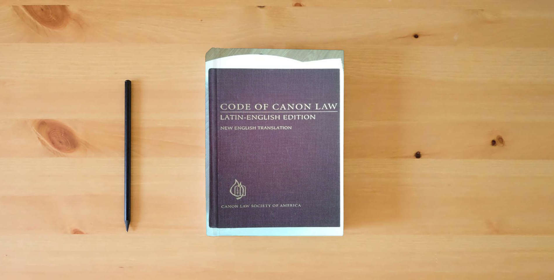 The book Code of Canon Law: Latin-English Edition, New English Translation (English and Latin Edition) is on the table