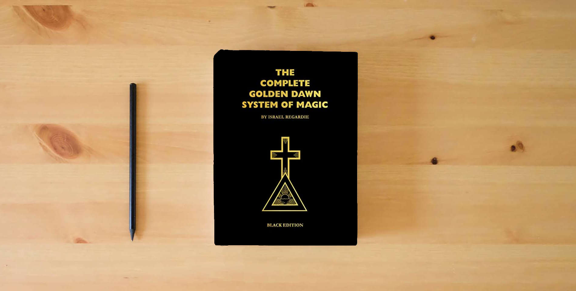 The book Complete Golden Dawn System of Magic Black Edition is on the table