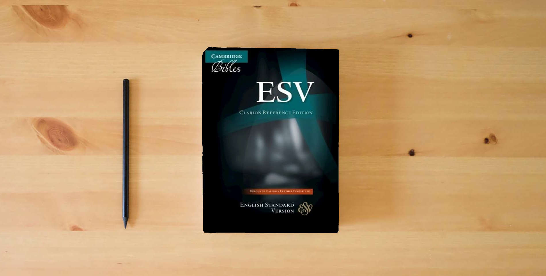 The book ESV Clarion Reference Bible, Burgundy Buffalo Calfskin Leather, Full Yapp, ES485:XLY is on the table