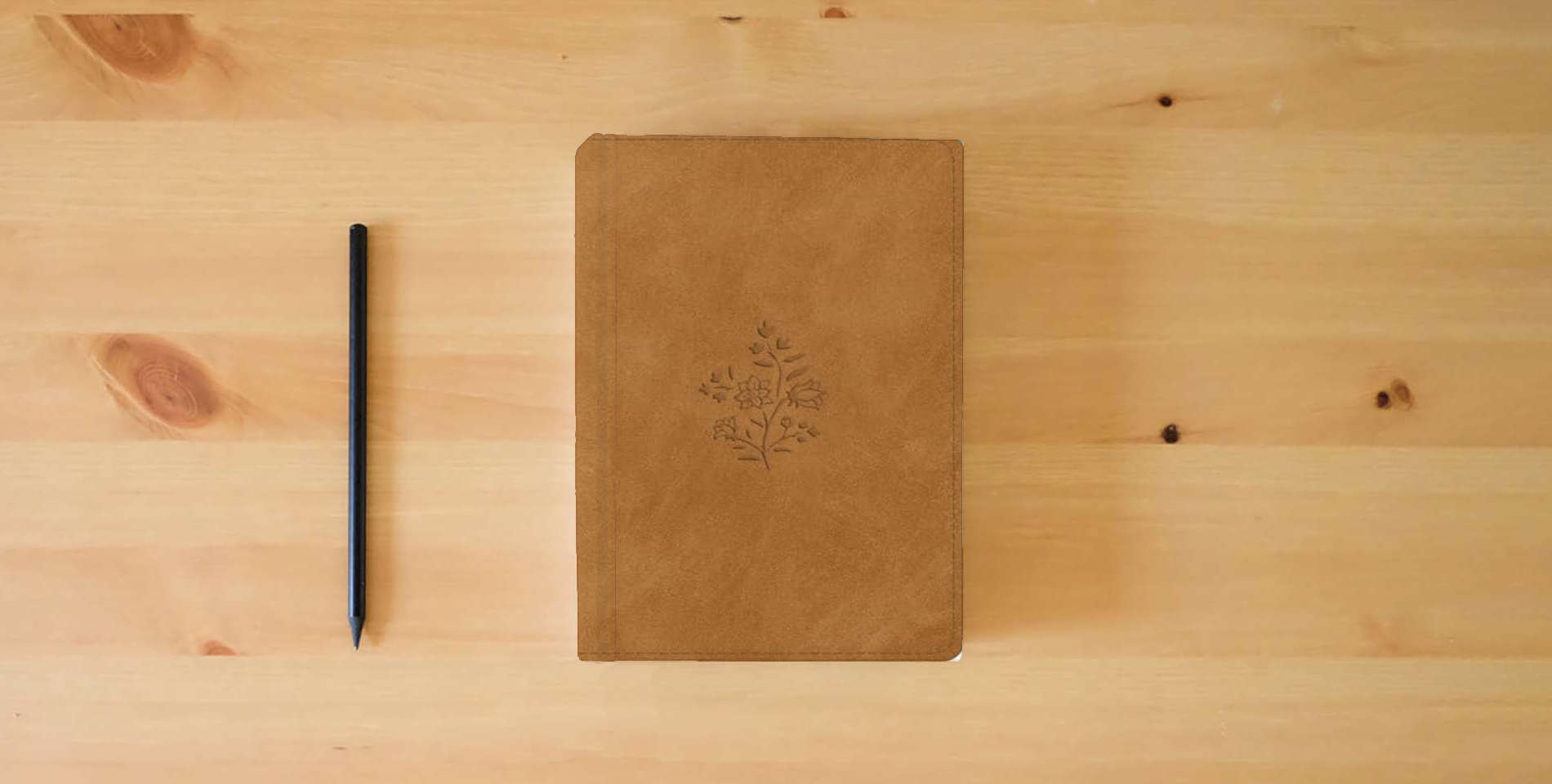 The book ESV Large Print Personal Size Bible, Red Letter, Thumb Indexed (TruTone, Nubuck Caramel, Wildflower Design): Holy Bible, English Standard Version is on the table