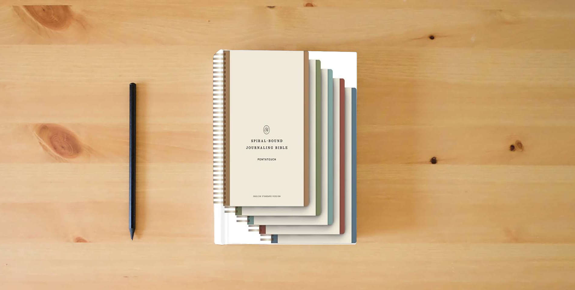 The book ESV Spiral-Bound Journaling Bible, Five-Volume Set (Hardcover) is on the table