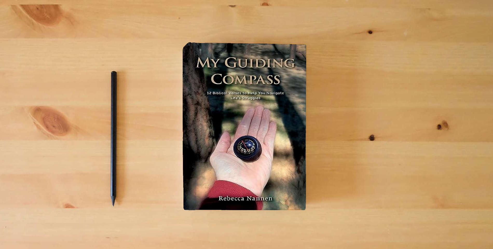 The book My Guiding Compass: 12 Biblical Verses to Help You Navigate Life's Struggles is on the table