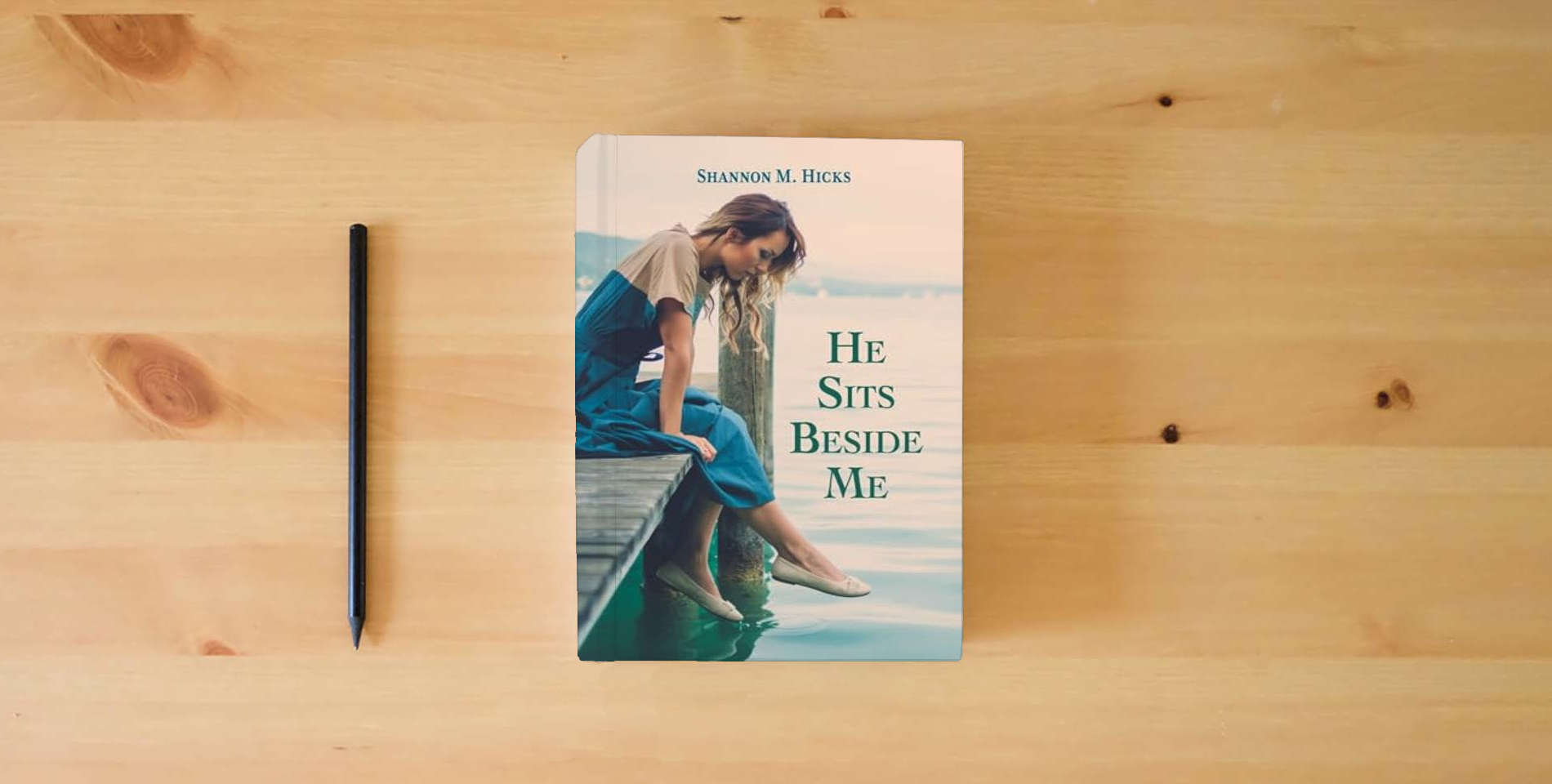 The book He Sits Beside Me is on the table