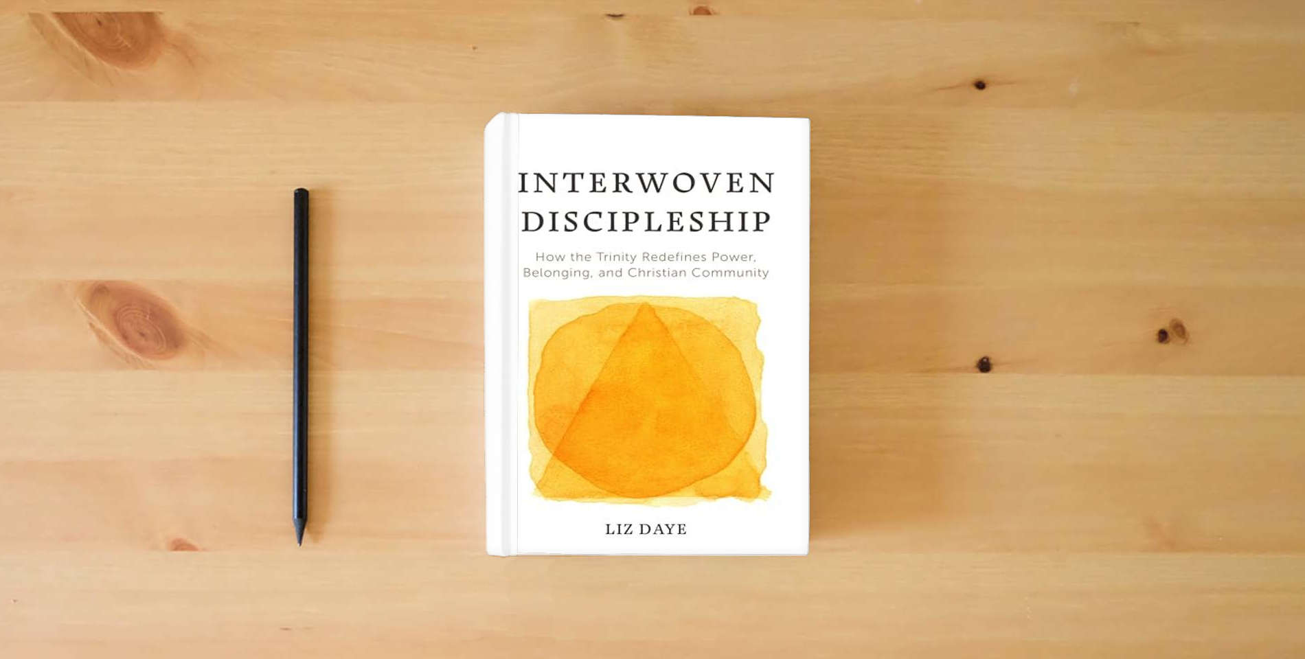 The book Interwoven Discipleship: How the Trinity Redefines Power, Belonging, and Christian Community is on the table