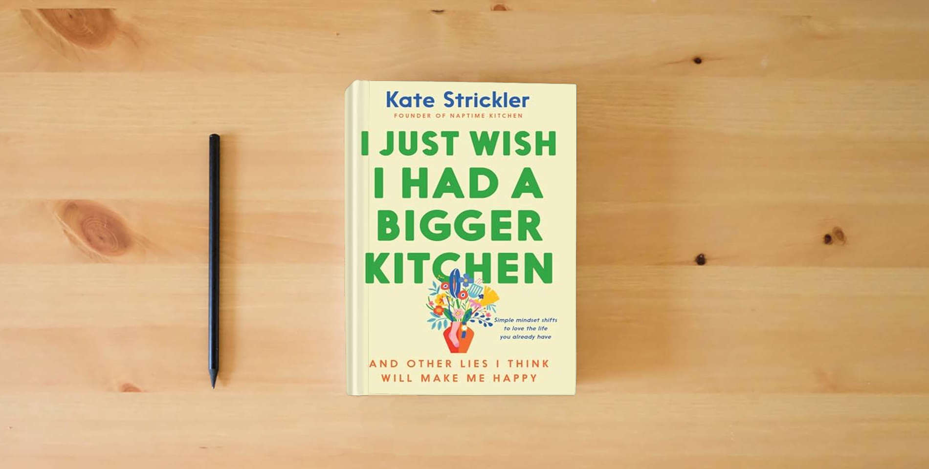 The book I Just Wish I Had a Bigger Kitchen: And Other Lies I Think Will Make Me Happy (Small Habits and Mindset Shifts to Find Contentment and Joy in Life) is on the table