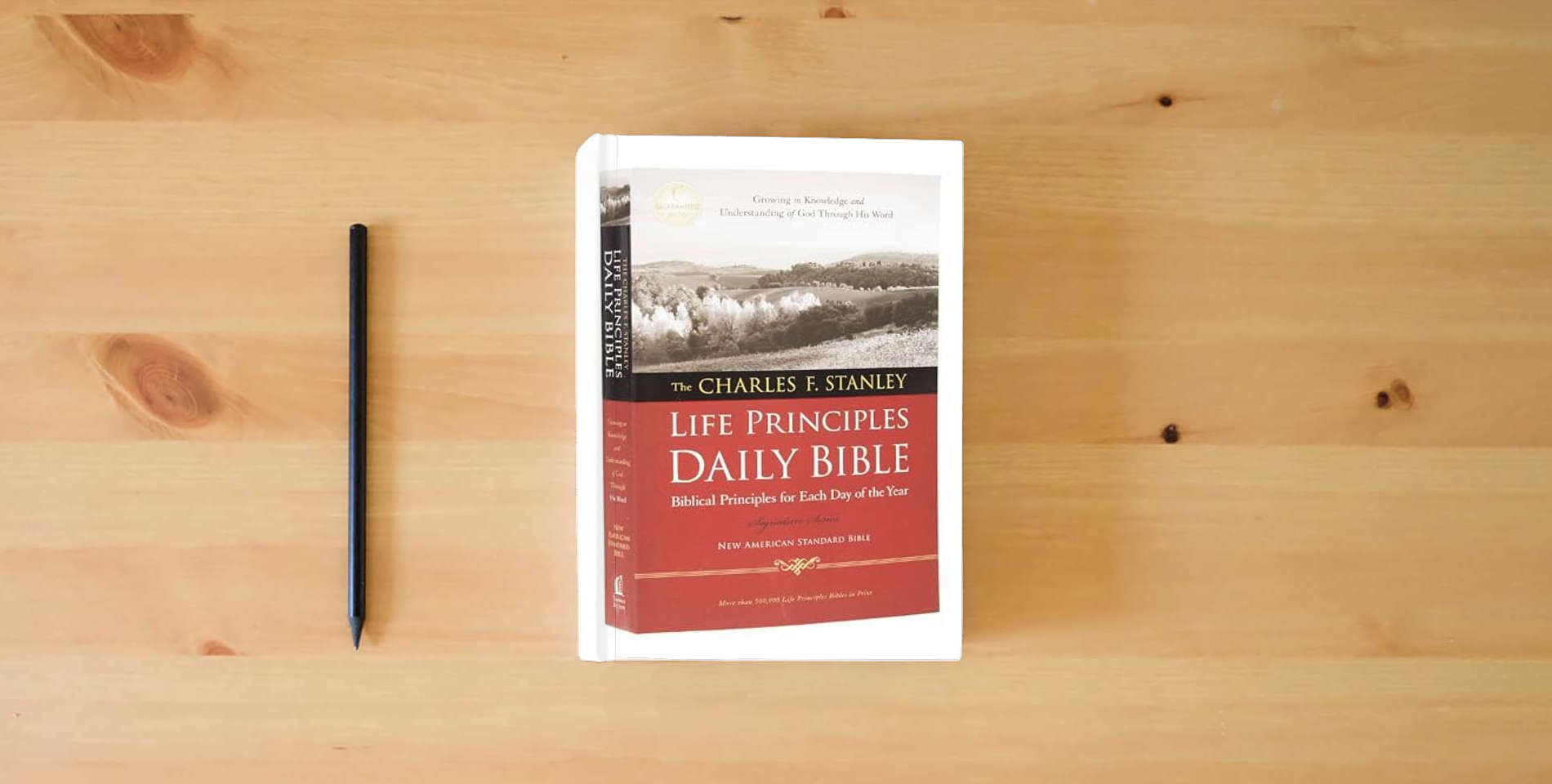 The book NASB, The Charles F. Stanley Life Principles Daily Bible, Paperback, 1995 Text: Holy Bible, New American Standard Bible is on the table
