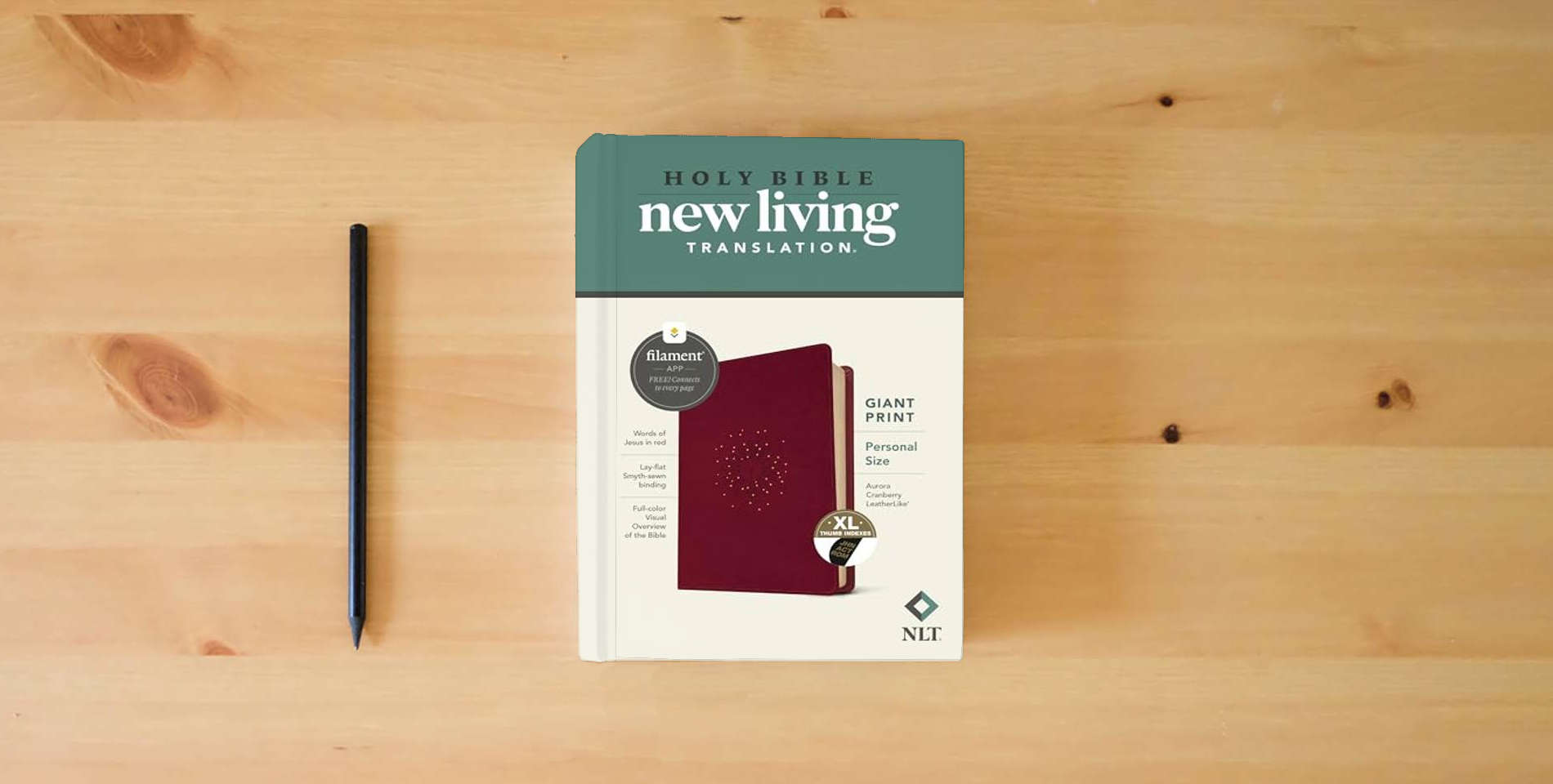 The book NLT Personal Size Giant Print Bible, Filament Enabled (LeatherLike, Aurora Cranberry, Indexed, Red Letter) is on the table