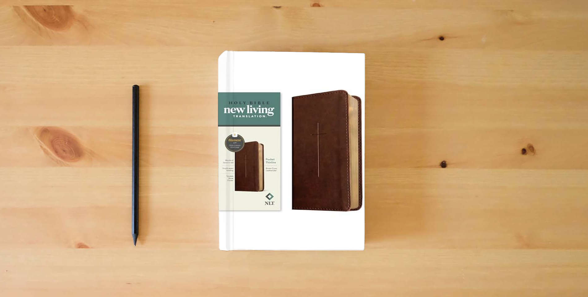 The book NLT Pocket Thinline Bible, Filament Enabled (LeatherLike, Brown Cross, Red Letter) is on the table