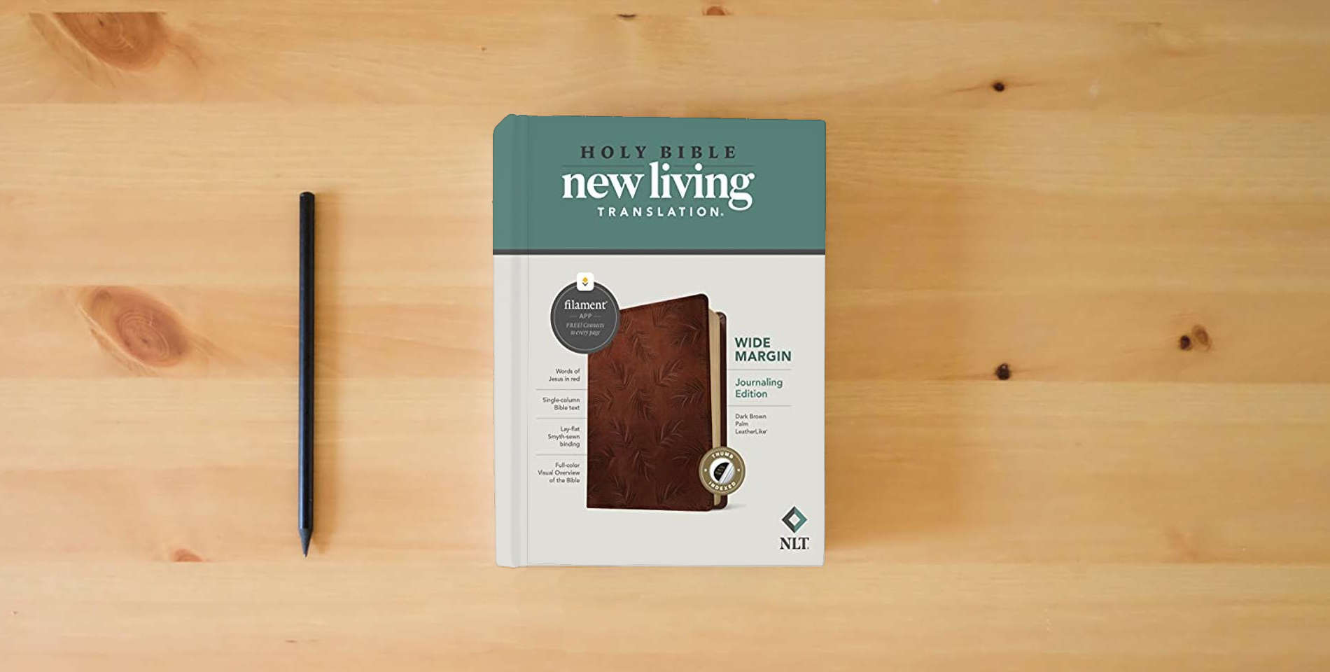 The book NLT Wide Margin Bible, Filament Enabled (LeatherLike, Dark Brown Palm, Indexed, Red Letter) is on the table