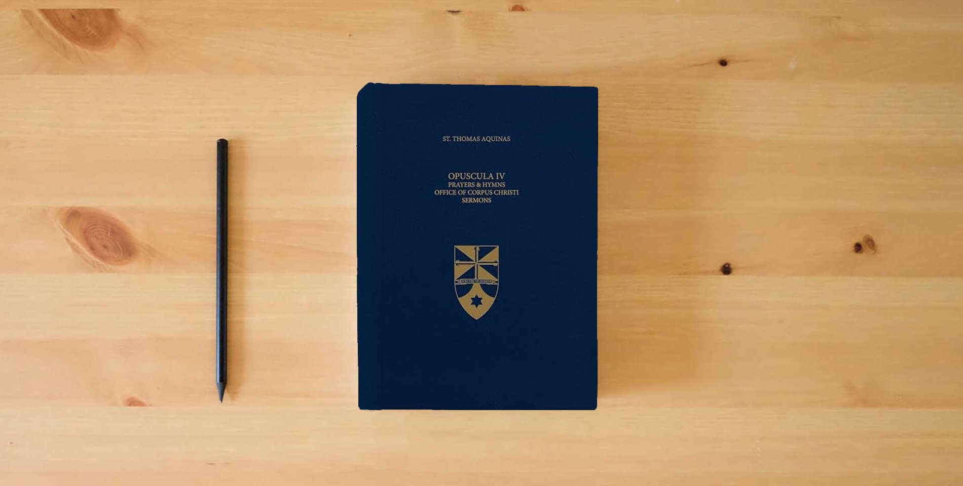 The book Opuscula IV Prayers & Hymns, Office of Corpus Christi, Sermons (Latin-English Opera Omnia) (Complete Works of St. Thomas Aquinas) is on the table