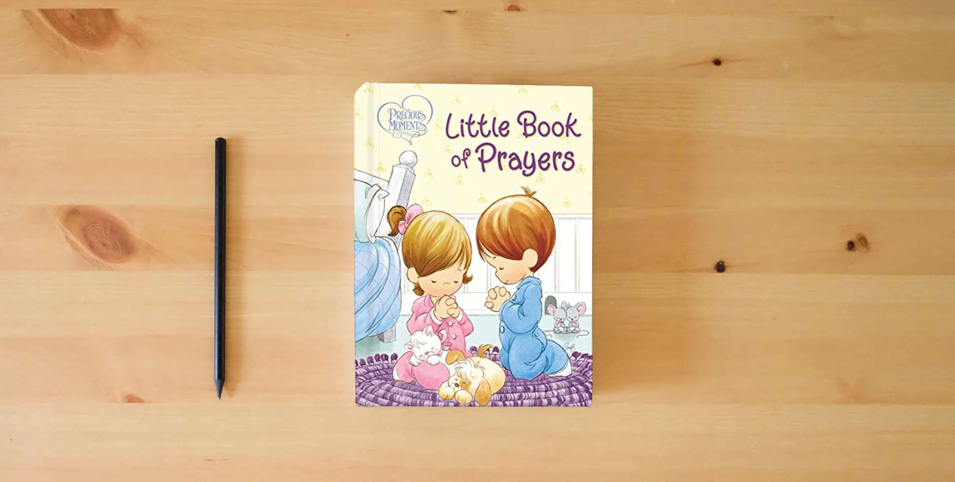The book Precious Moments: Little Book of Prayers is on the table