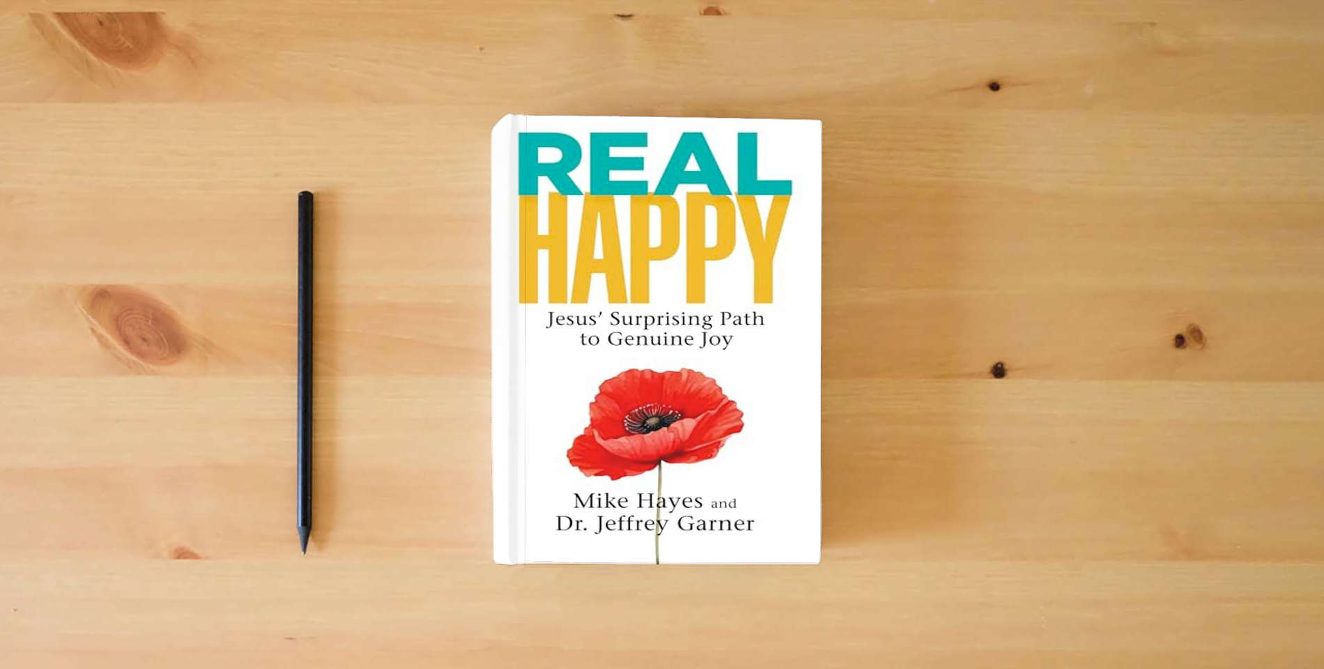 The book Real Happy: Jesus' Surprising Path to Genuine Joy is on the table
