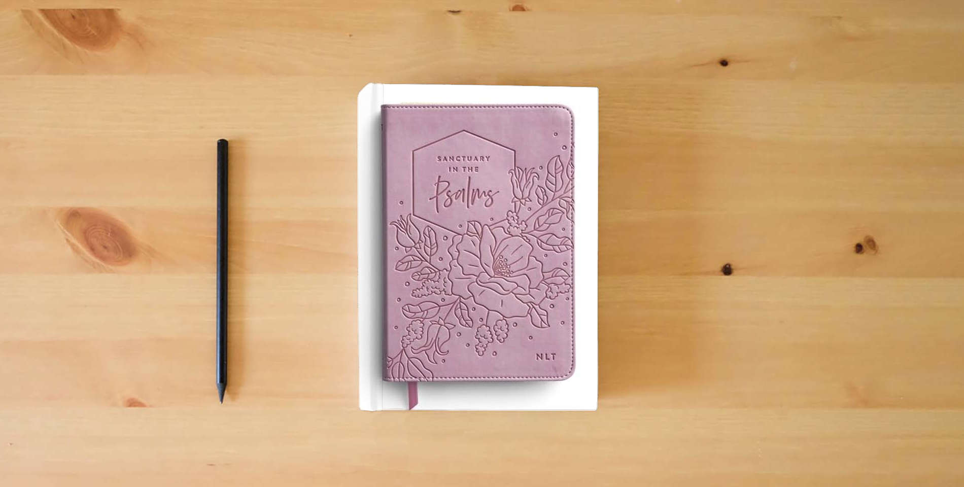 The book Sanctuary in the Psalms - NLT Scripture Book is on the table