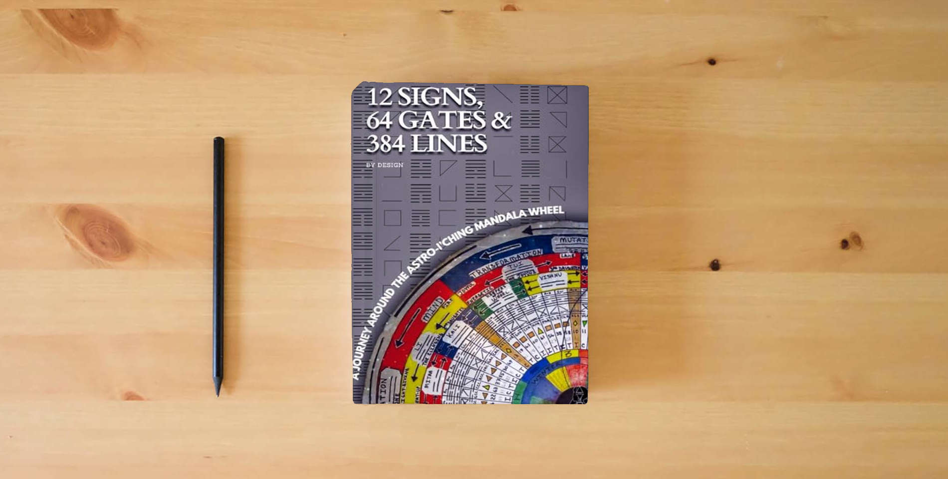 The book 12 SIGNS, 64 GATES & 384 LINES BY DESIGN: A JOURNEY AROUND THE ASTRO-I’CHING MANDALA WHEEL is on the table
