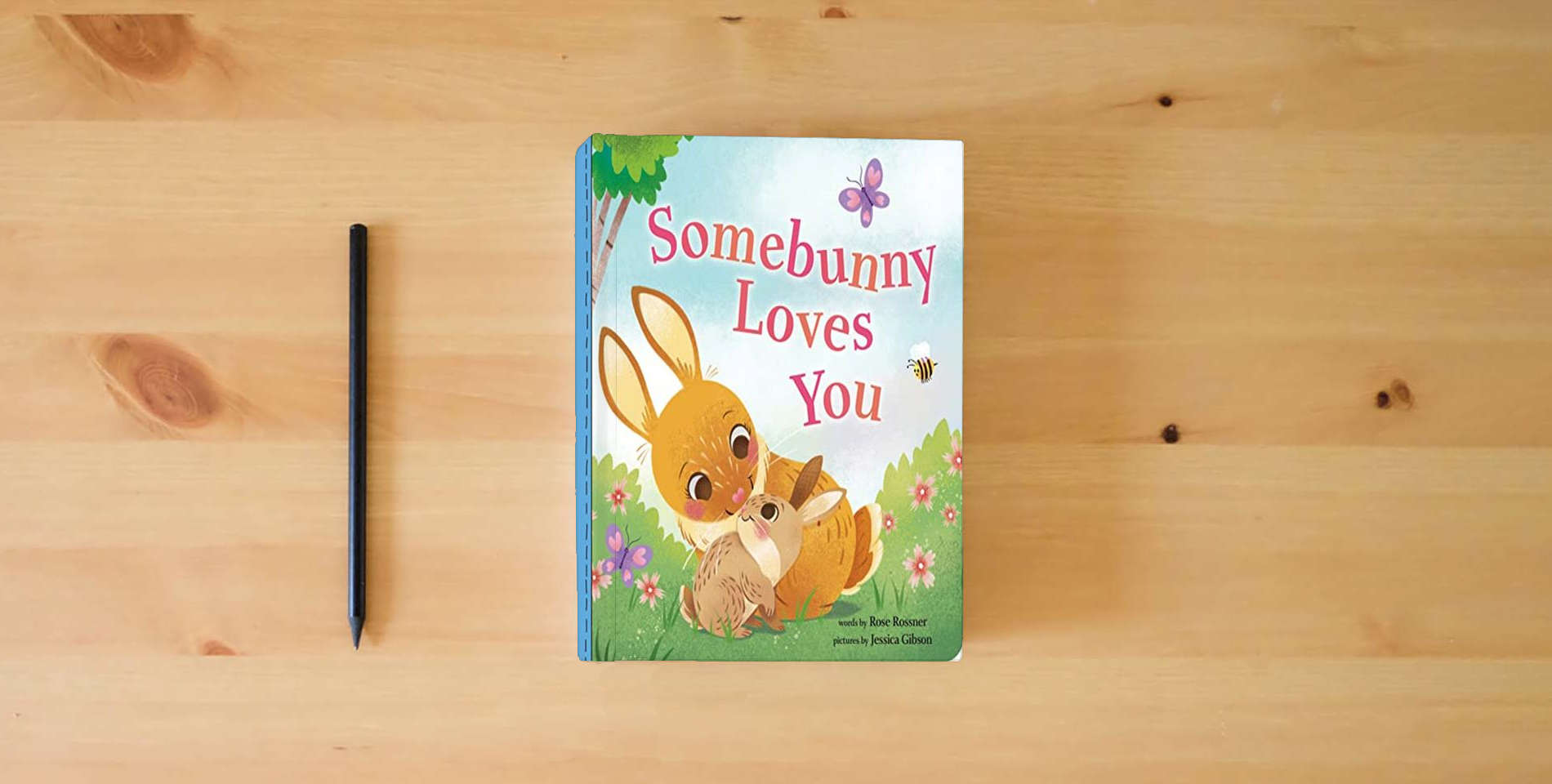 The book Somebunny Loves You: A Sweet and Silly Easter Board Book for Babies and Toddlers (Punderland) is on the table
