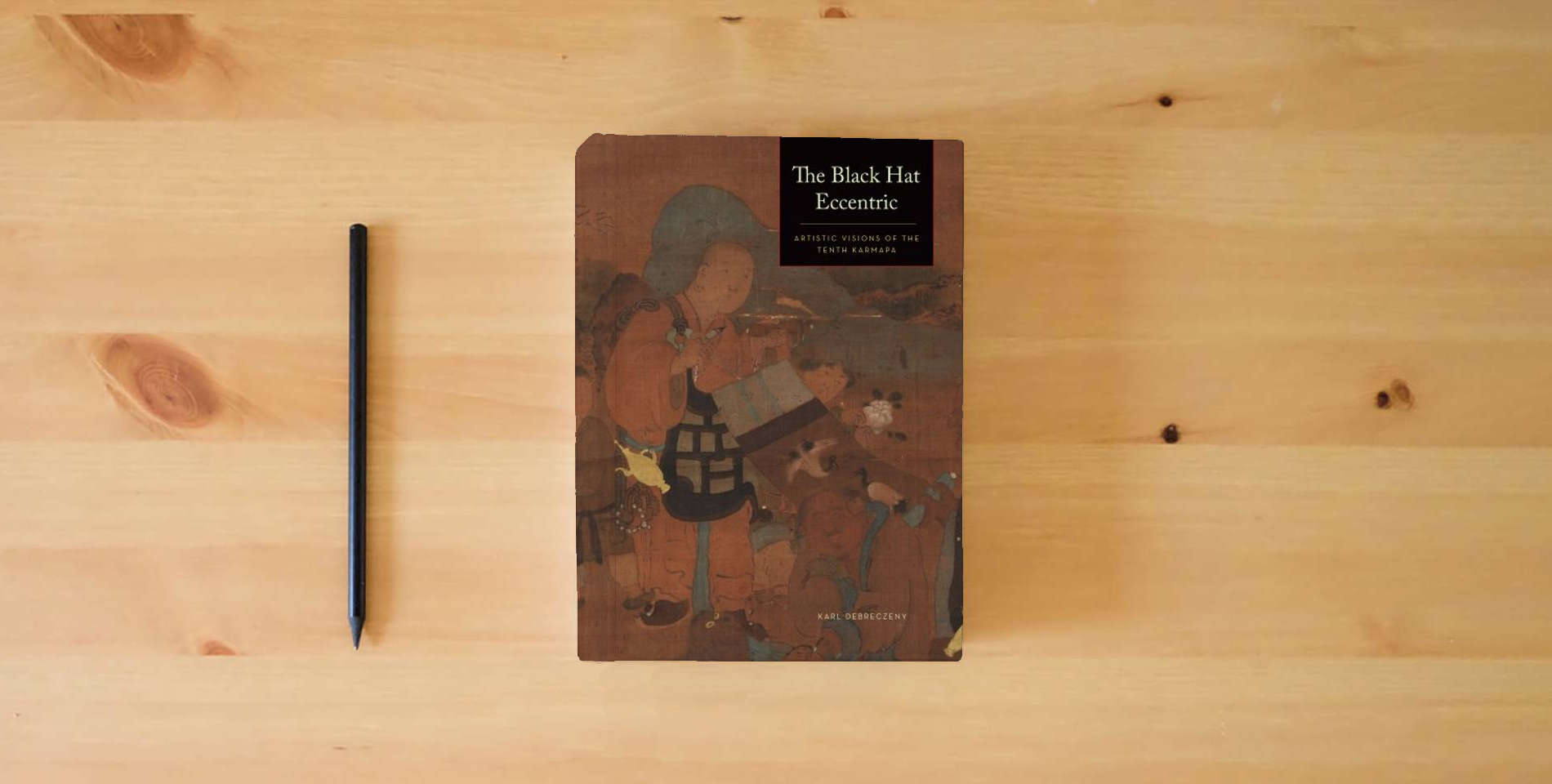 The book The Black Hat Eccentric: Artistic Visions of the Tenth Karmapa is on the table