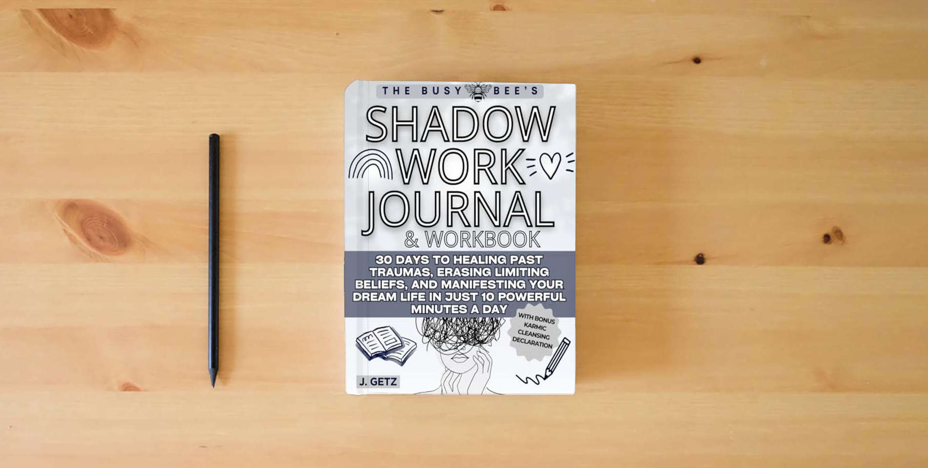 The book The Busy Bee's SHADOW WORK Journal and Workbook: 30 Days to Healing Past Traumas, Erasing Limiting Beliefs, and Manifesting Your Dream Life in Just 10 Powerful Minutes a Day is on the table