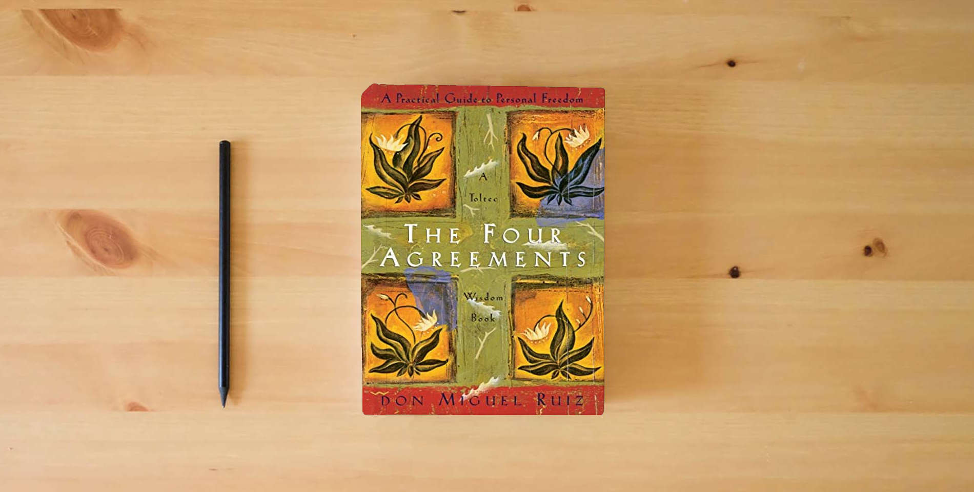 The book The Four Agreements: A Practical Guide to Personal Freedom (A Toltec Wisdom Book) is on the table