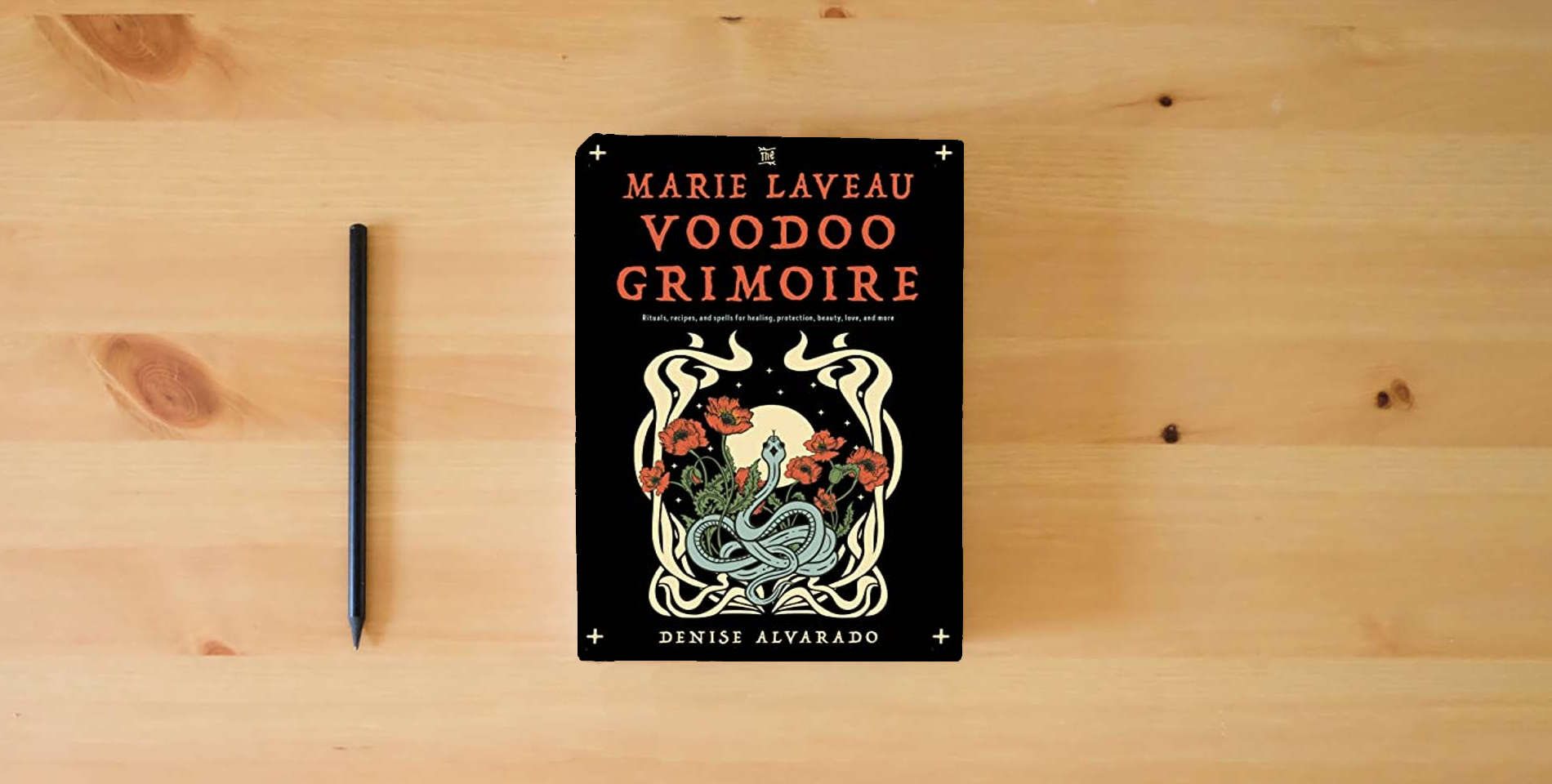The book The Marie Laveau Voodoo Grimoire: Rituals, Recipes, and Spells for Healing, Protection, Beauty, Love, and More is on the table