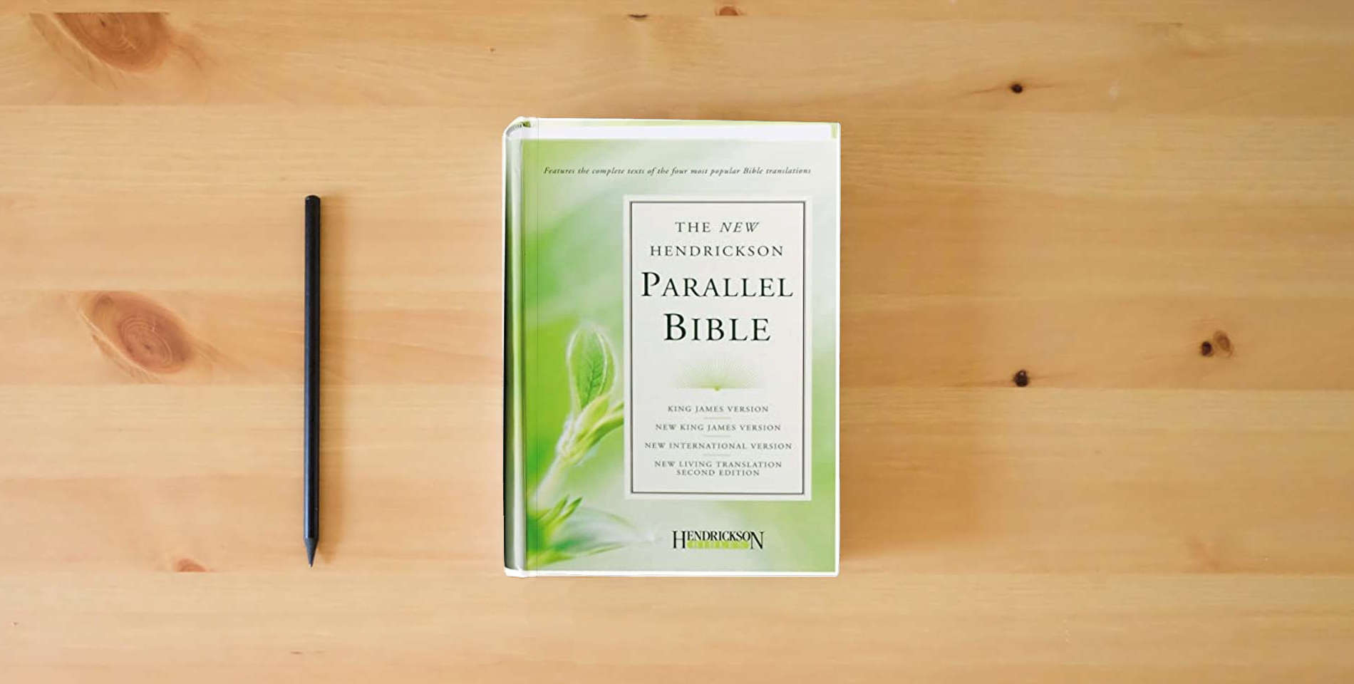 The book The New Hendrickson Parallel Bible: King James Version, New King James Version, New International Version, New Living Translation, 2nd Ed is on the table