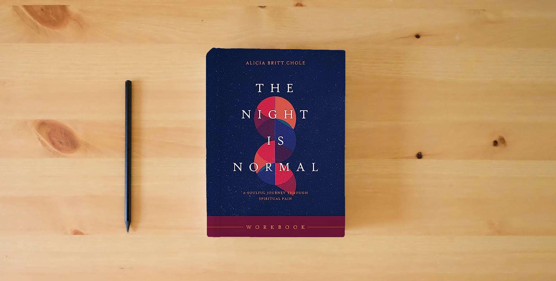 The book The Night Is Normal Workbook: A Soulful Journey through Spiritual Pain is on the table