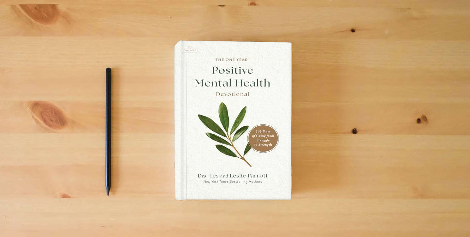 The book The One Year Positive Mental Health Devotional: 365 Days of Going from Struggle to Strength is on the table
