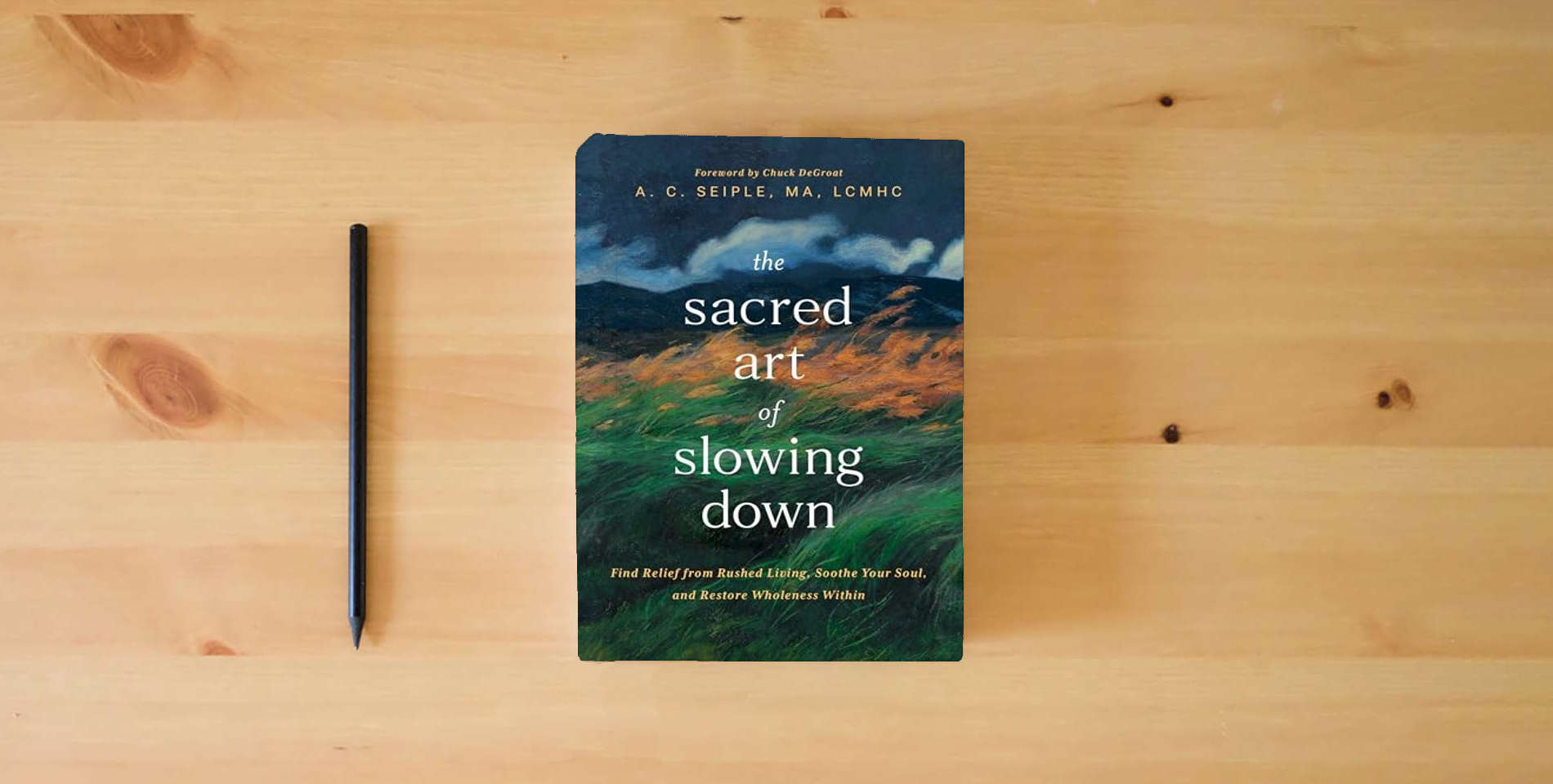 The book The Sacred Art of Slowing Down: Find Relief from Rushed Living, Soothe Your Soul, and Restore Wholeness Within is on the table