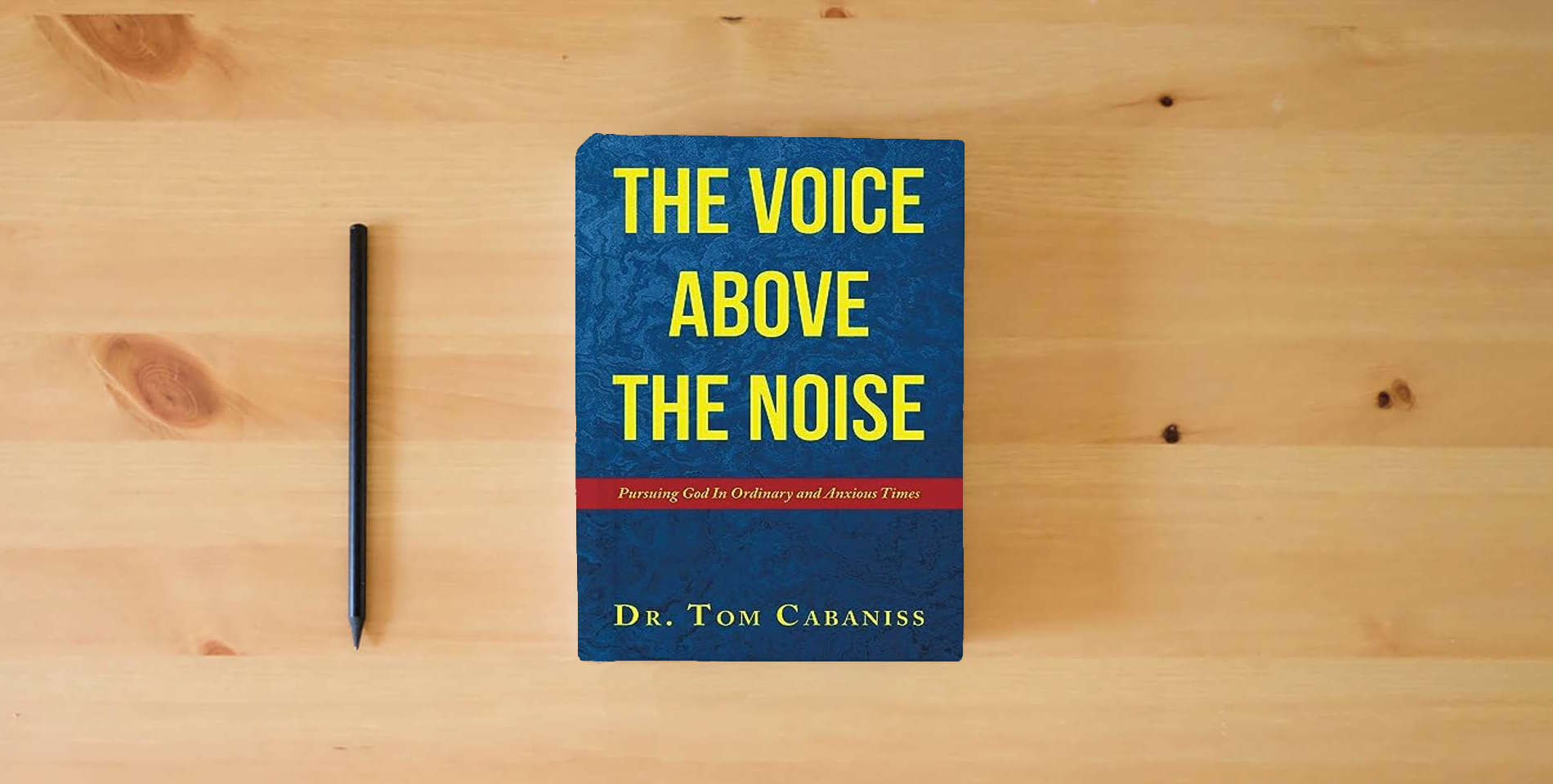 The book The Voice Above The Noise: Pursuing God In Ordinary and Anxious Times is on the table