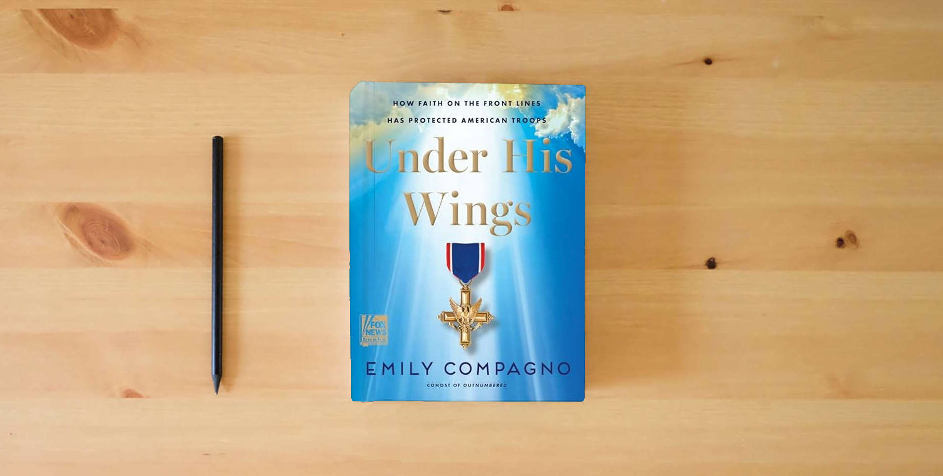 The book Under His Wings: How Faith on the Front Lines Has Protected American Troops is on the table