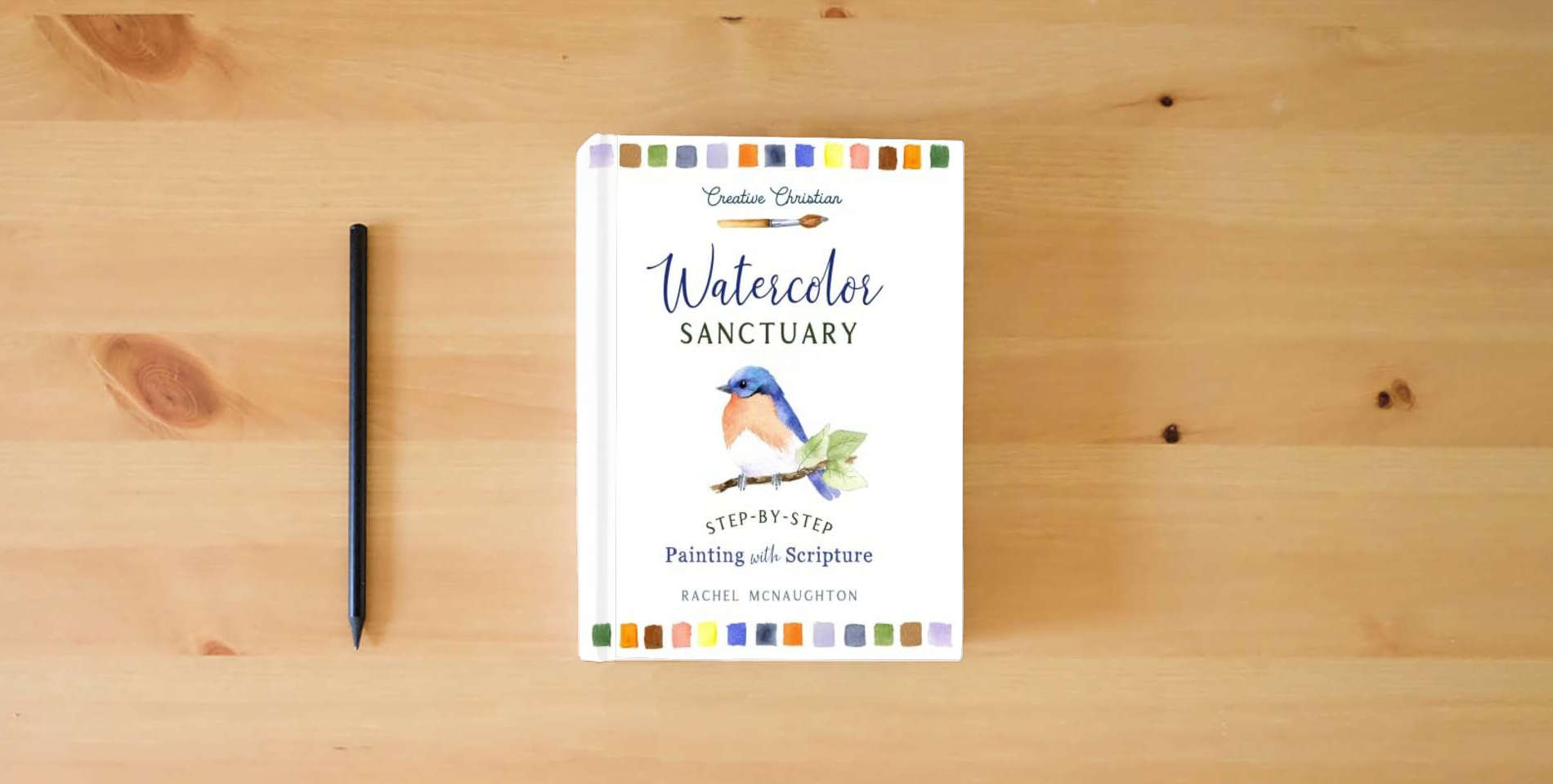 The book Watercolor Sanctuary: Step-by-Step Painting with Scripture (Creative Christian) is on the table