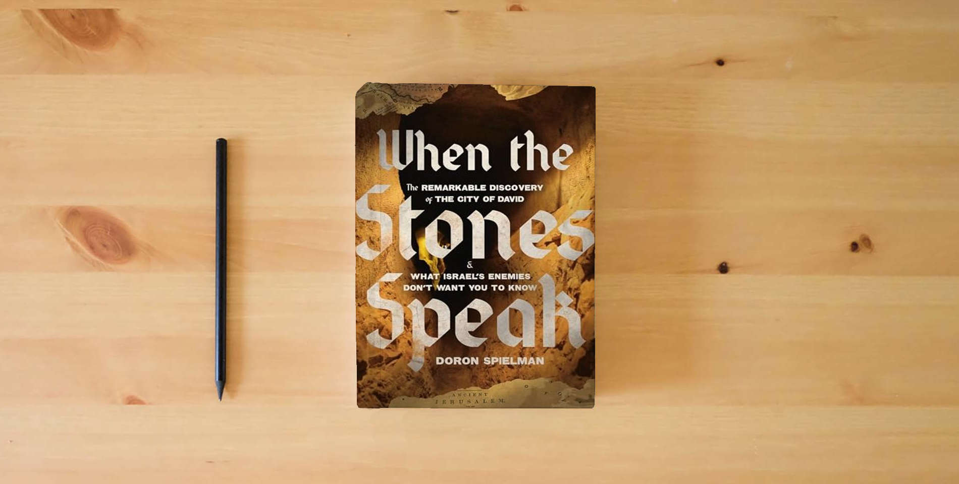 The book When the Stones Speak: The Remarkable Discovery of the City of David and What Israel's Enemies Don't Want You To Know is on the table