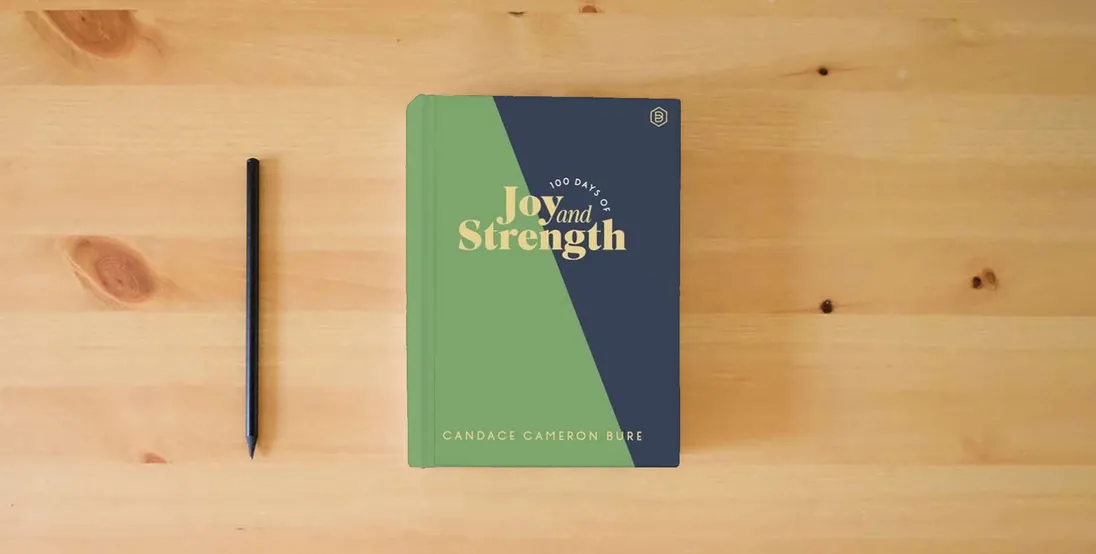 The book 100 Days of Joy and Strength: Daily Devotions to Help You Find Overwhelming Peace on Busy Days - The Perfect Devotional Gifts for Christian Women} is on the table