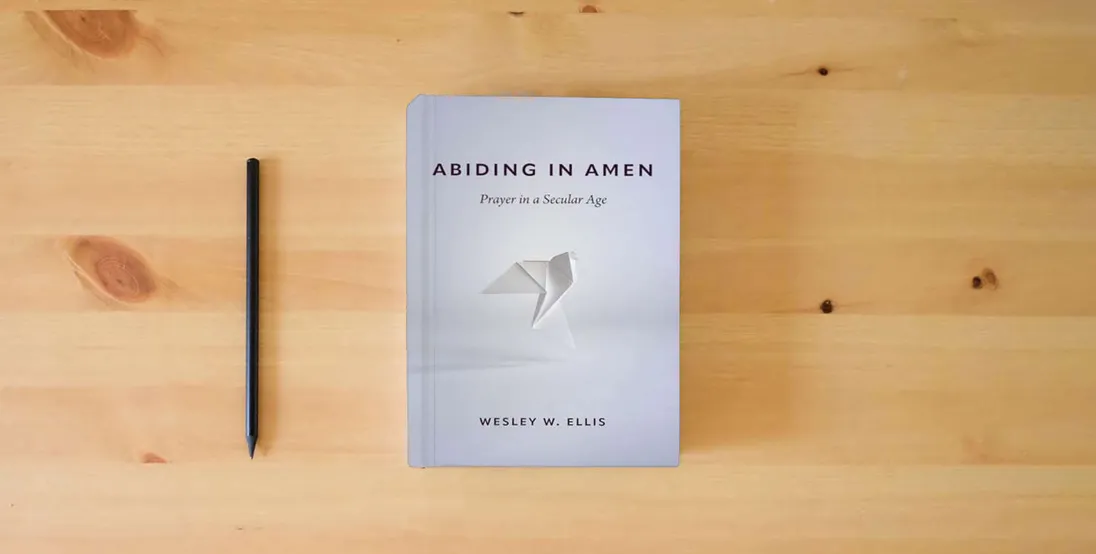 The book Abiding in Amen: Prayer in a Secular Age} is on the table