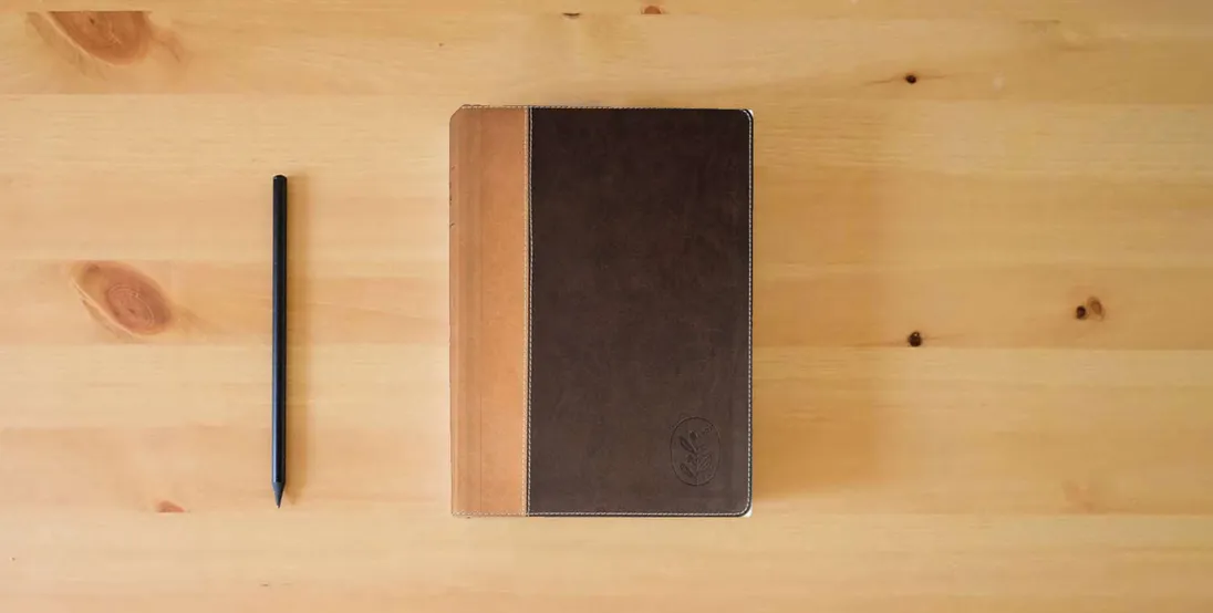 The book Anabaptist Community Bible: Hardcover Edition} is on the table