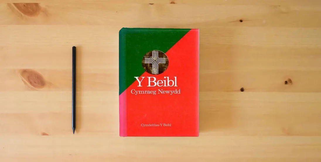 The book Y Beibl Cymraeg Newydd (New Welsh Bible)} is on the table