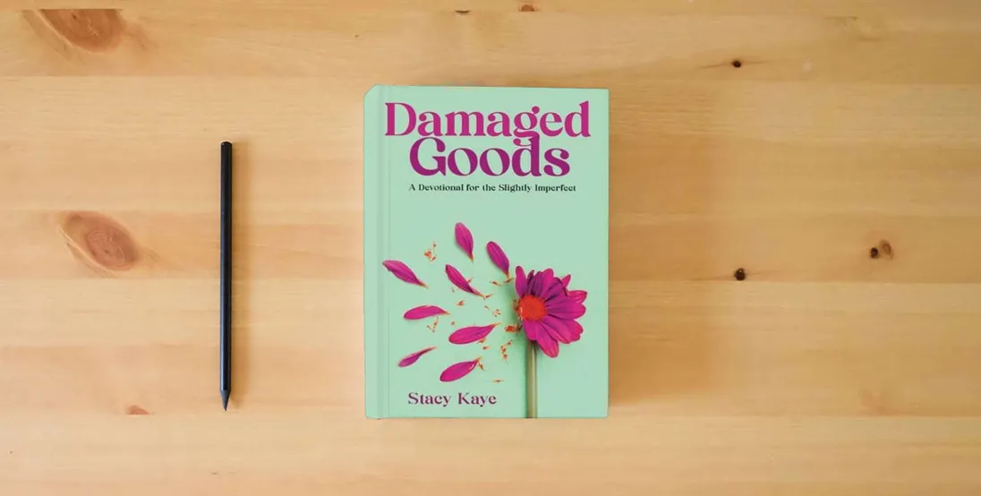 The book Damaged Goods: A Devotional for the Slightly Imperfect} is on the table