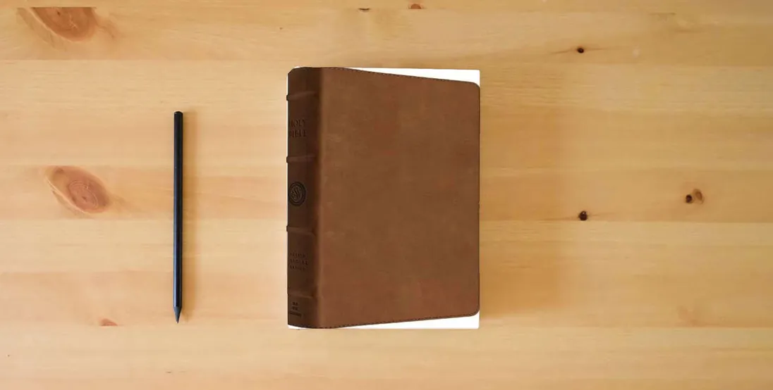 The book ESV Heirloom Bible, Heritage Edition (Cowhide, Full Yapp, British Tan)} is on the table