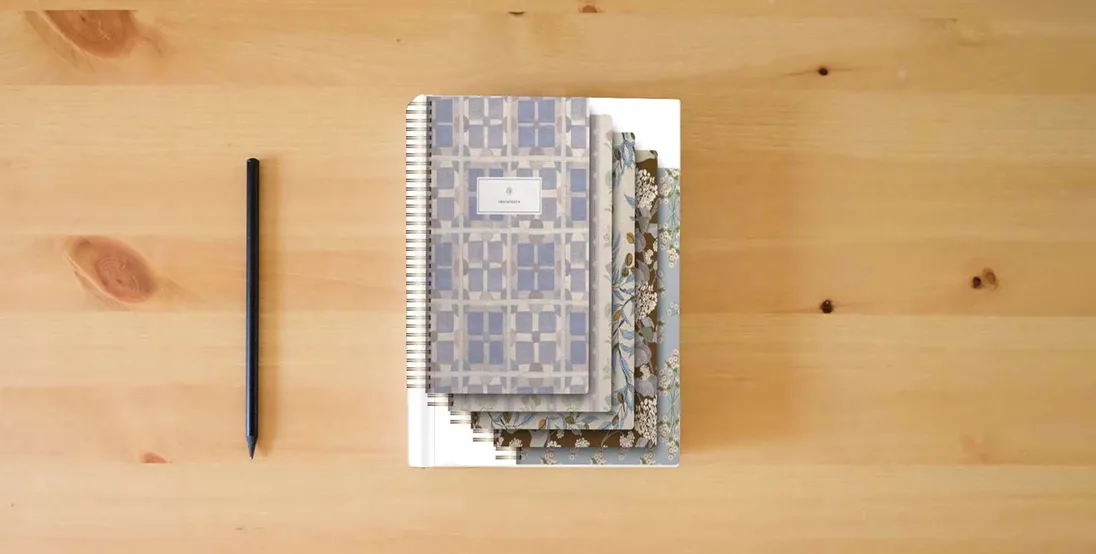 The book ESV Spiral-Bound Journaling Bible, Five-Volume Set (Hardcover, Cover Artwork by Lulie Wallace)} is on the table