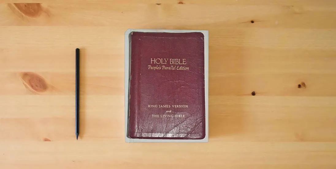 The book Holy Bible: People's Parallel Edition, King James Version and the Living Bible} is on the table