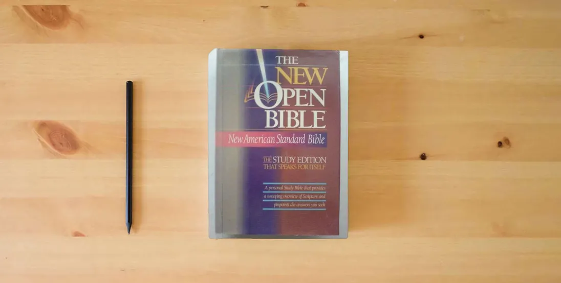 The book Holy Bible: The New Open Bible, Study Edition, New American Standard Bible} is on the table