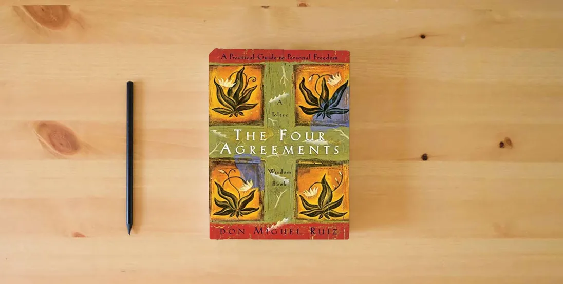 The book The Four Agreements: A Practical Guide to Personal Freedom (A Toltec Wisdom Book)} is on the table