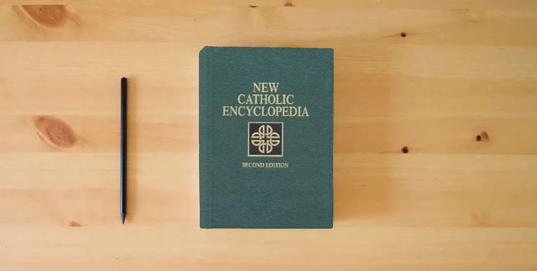 The book The New Catholic Encyclopedia, 2nd Edition (15 Volume Set)} is on the table
