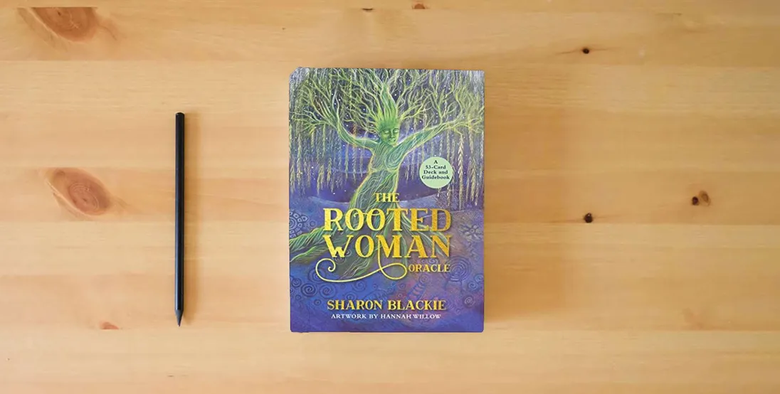 The book The Rooted Woman Oracle: A 53-Card Deck and Guidebook} is on the table