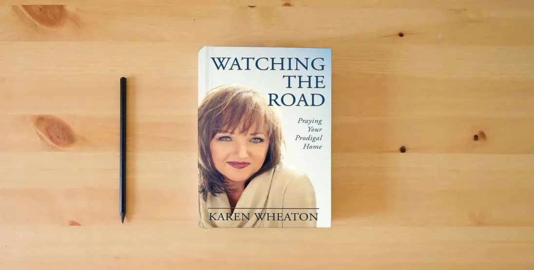 The book Watching The Road: Praying Your Prodigal Home} is on the table
